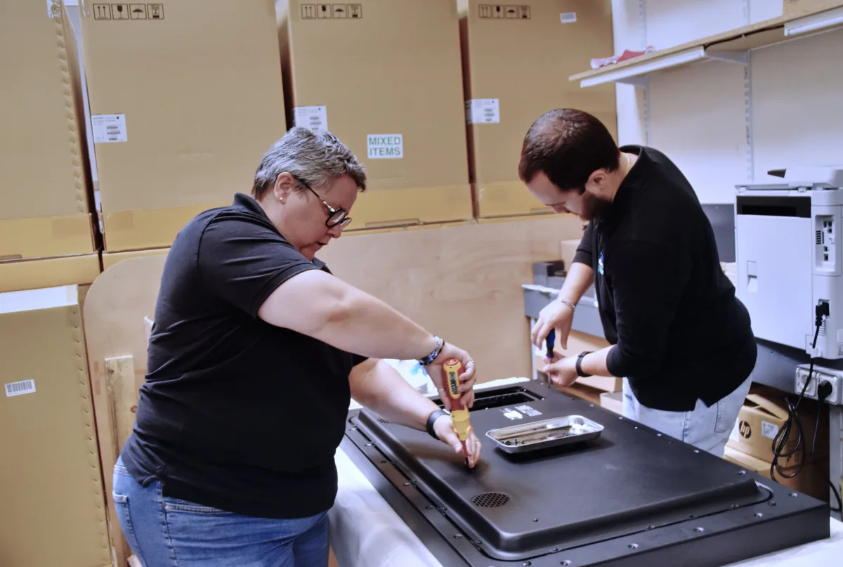 Deux techniciens Digitel Solutions préparent un écran interactif avant installation